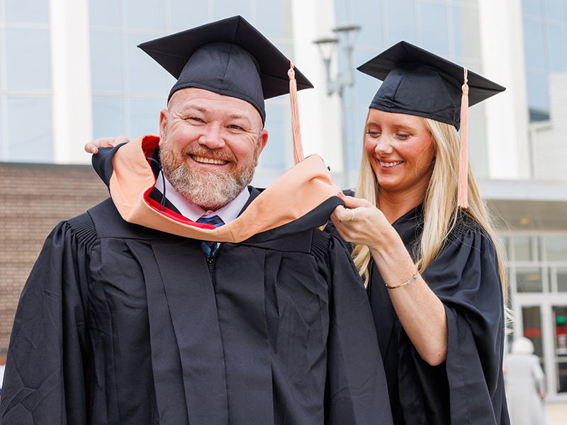 Anna Welborn, a cum laude graduate of the BSN program in the School of Nursing, helps her dad, George Doby, get ready for the University of Mississippi Medical Center's 68th annual Commencement. Dolby, a summa cum laude graduate, earned his Master of Science in Nursing.
